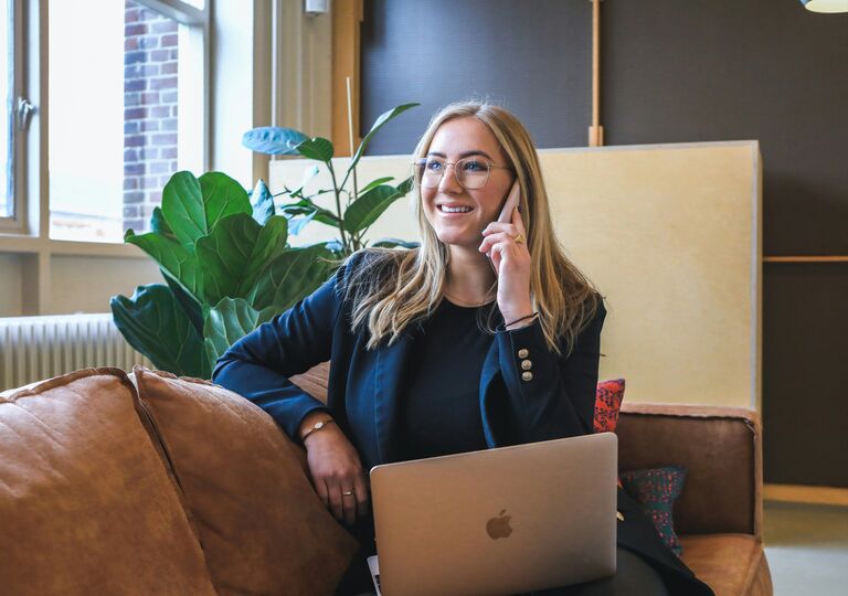 a person talking on the phone and working on laptop