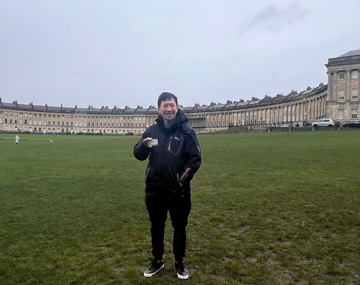A photo of Eagle Yip with his Birthday Bus Month Pass at Bath's Royal Crescent