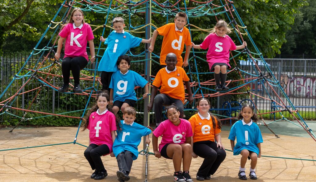 Kids in playground wearing t-shirts that spell out 'Kids Go Free'