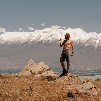 Fit younger man with six pack drinking Ka'Chava with beautiful snowcapped mountains in the background