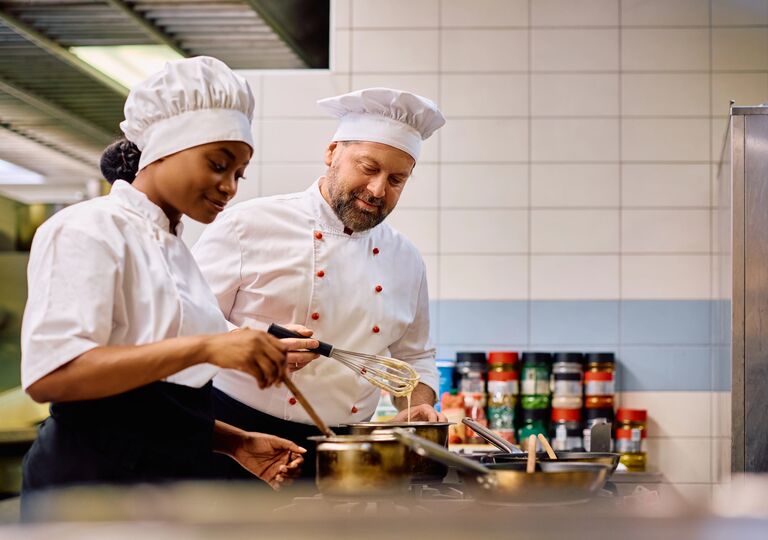 two chefs preparing food in a restaurant kitchen