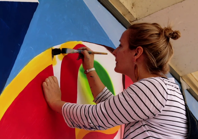 a woman painting a mural