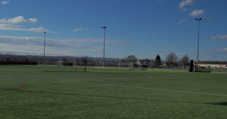 football pitch with floodlights and blue sky