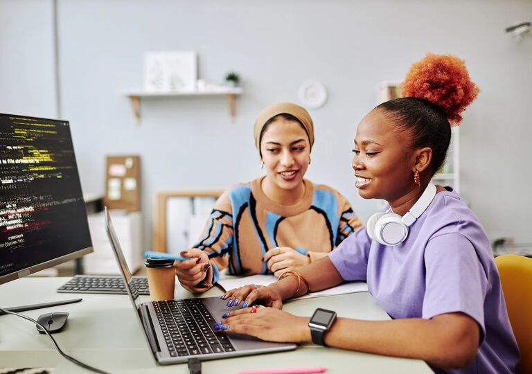 young woman receiving help from mentor on a laptop