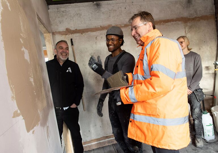 Group of smiling people plastering a wall