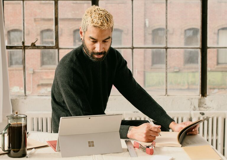 person making notes from a laptop
