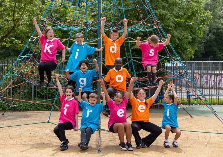 children sit on play equipment wearing t-shirts to spell out 'kids go free'
