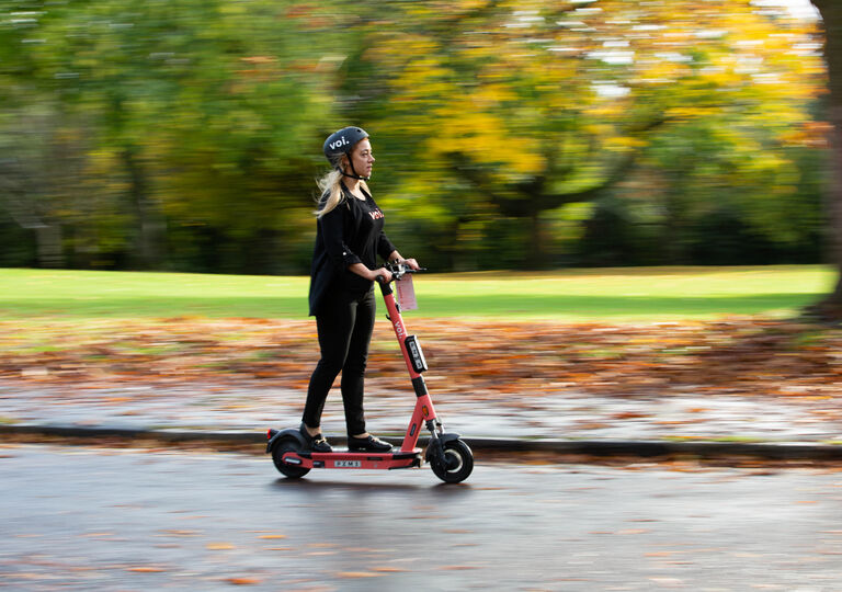 Someone riding an electric scooter through a blurry autumn landscape
