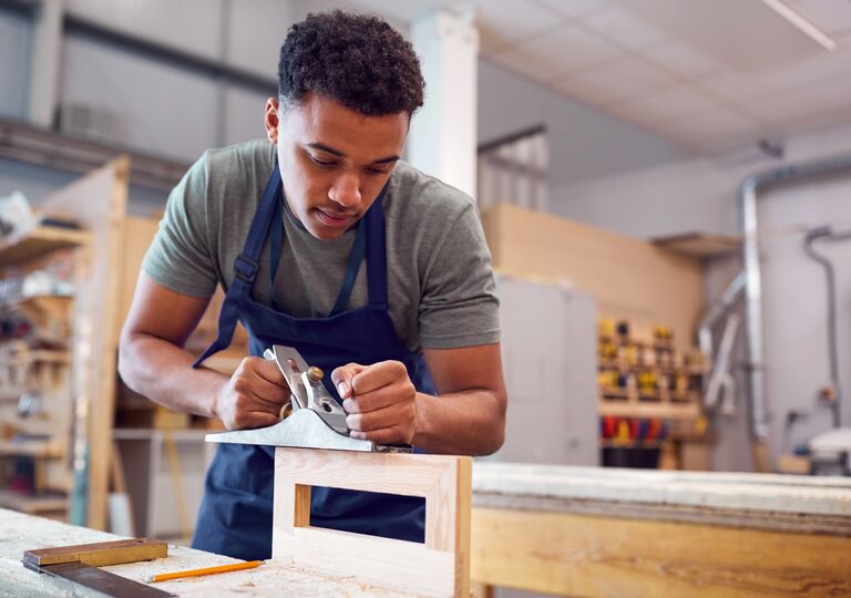 young person using a wood plane