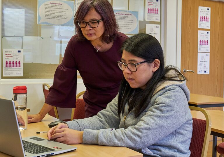 Two people working at laptop