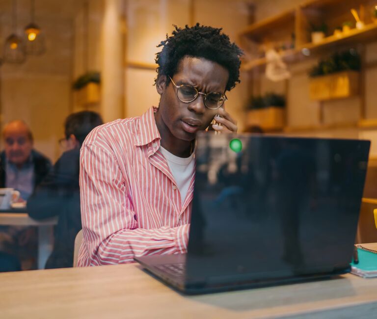 Man working at laptop, on the phone