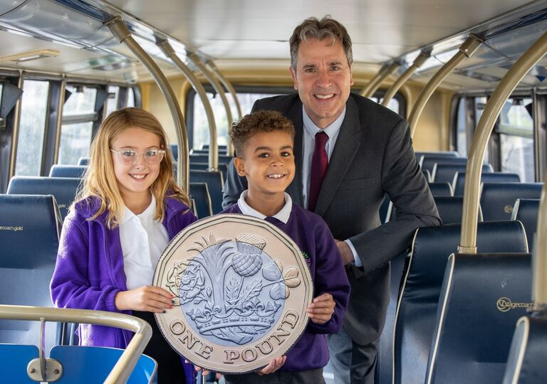 Metro Mayor Dan Norris with children from Holymead Primary School on board a bus with a giant pound coin