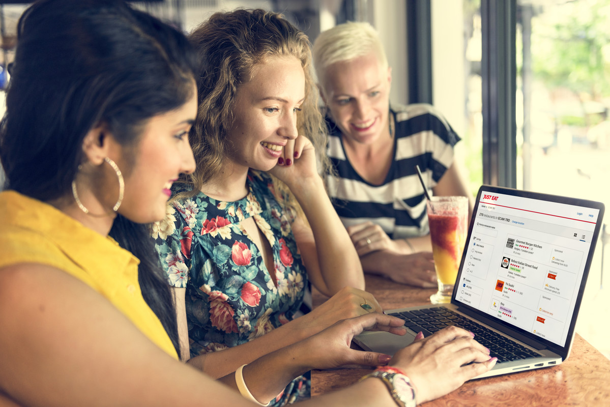 Three women looking at Just Eat on a computer