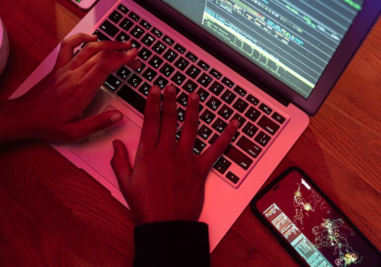 hands on a laptop keyboard, next to a smartphone