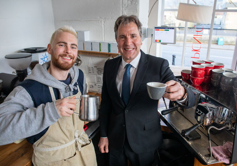 Mayor and barista holding up coffees