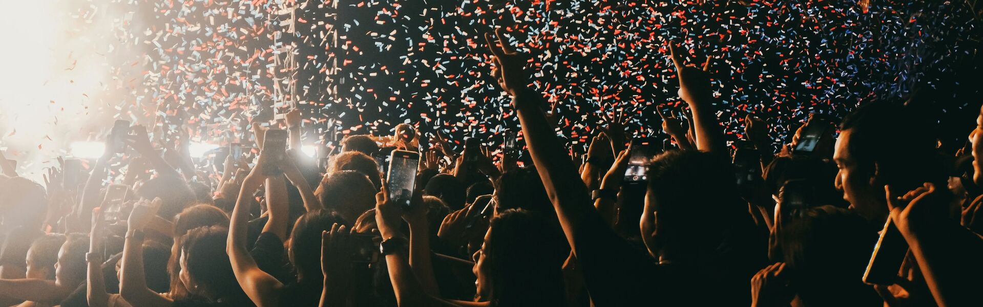Hands in the air celebrating in front of confetti on stage