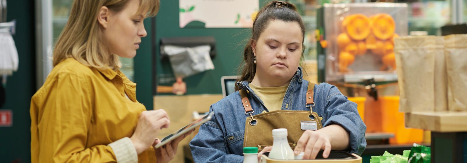 young person working in a shop with support from mentor