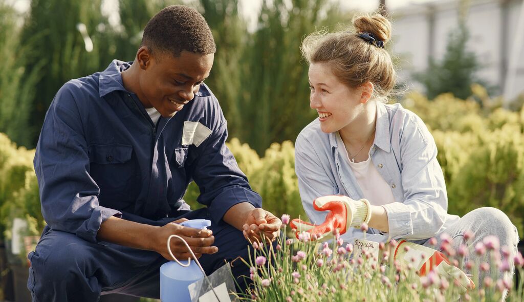 two young people talking to each other while tending to plants