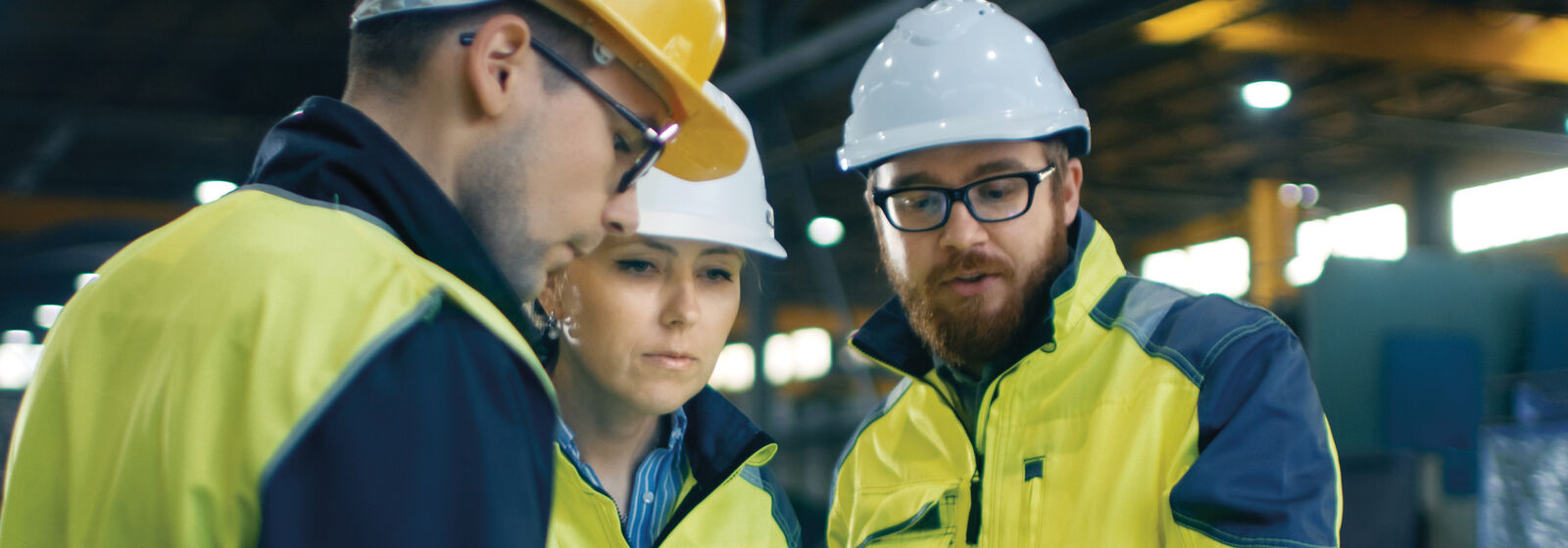 People in high-vis and hard hats are pictured, looking at plans.