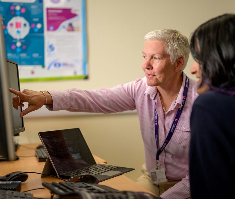 Two people pointing at a screen