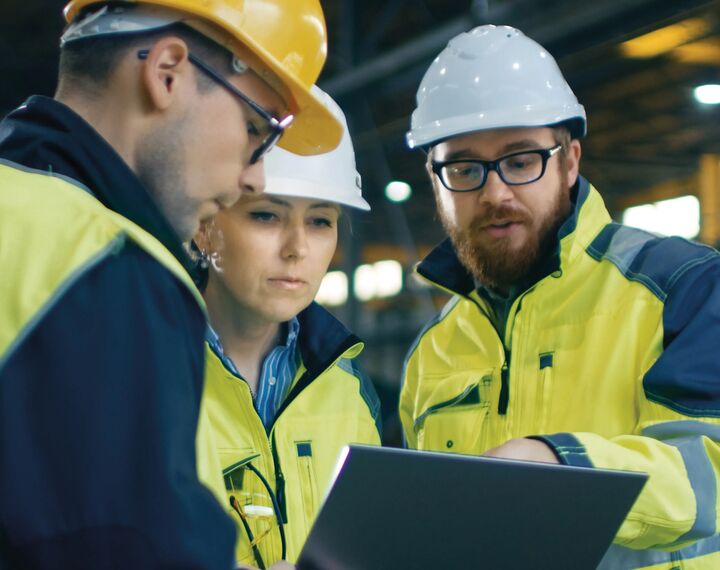 People in high-vis and hard hats are pictured, looking at plans.