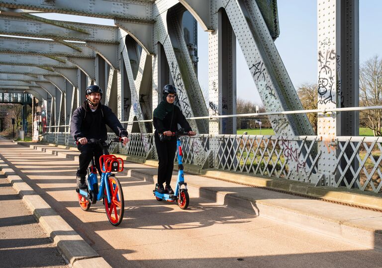two people riding an e-bike and e-scooter