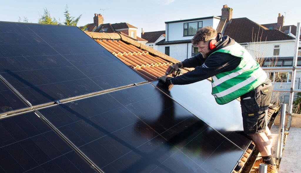 Person installs solar panel on roof