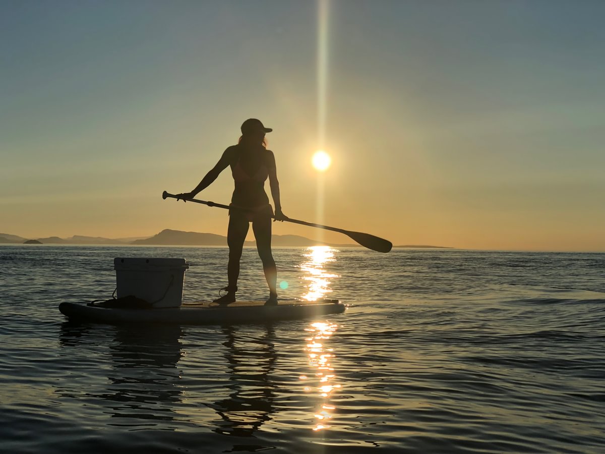 woman on paddle board during sunset on calm water