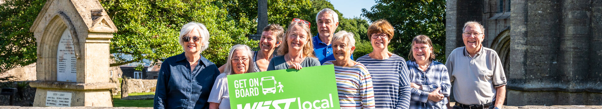 Local community group behind one of the WESTlocal schemes holding a WESTlocal people powered transport sign in front of their WESTlocal bus