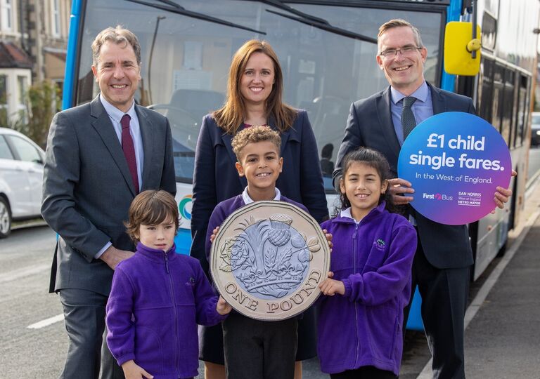 Stood in front of a bus are Metro Mayor Dan Norris, Rob Pymm (Commercial Director, First West of England) and Rachel Geliamassi (Managing Director, Stagecoach West) as well as the children of Holymead Primary School holding a giant pound coin