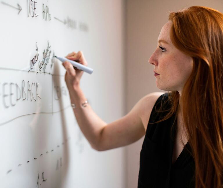 Person writing illegibly on whiteboard