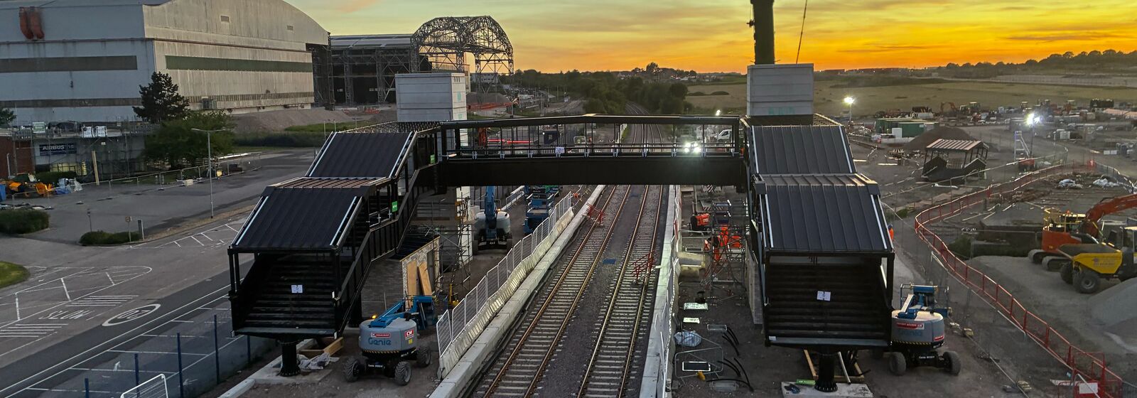view of footbridge over railway tracks at sunrise