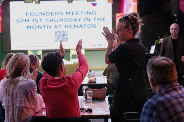 People clapping, stage in background says 