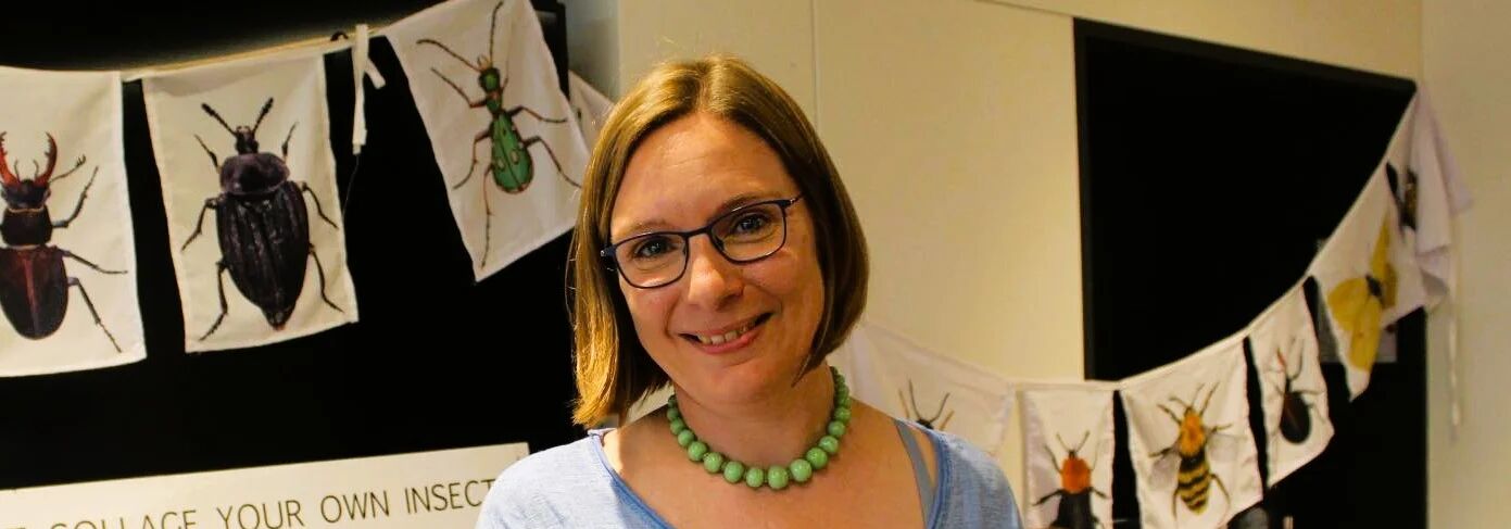 Smiling person in front of posters of bugs