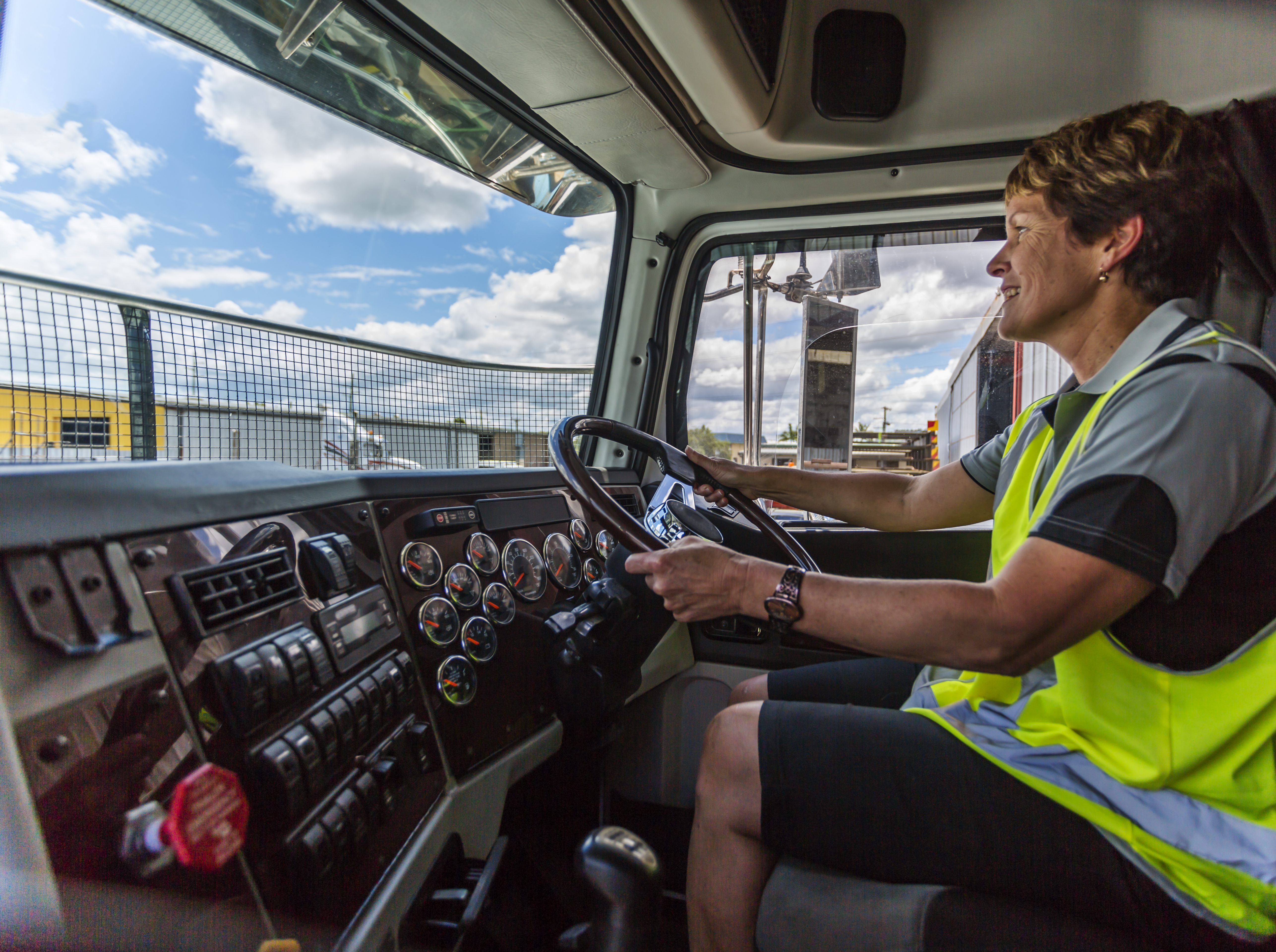 Empowered happy woman driving a truck in the transport industry wearing high visibility clothing