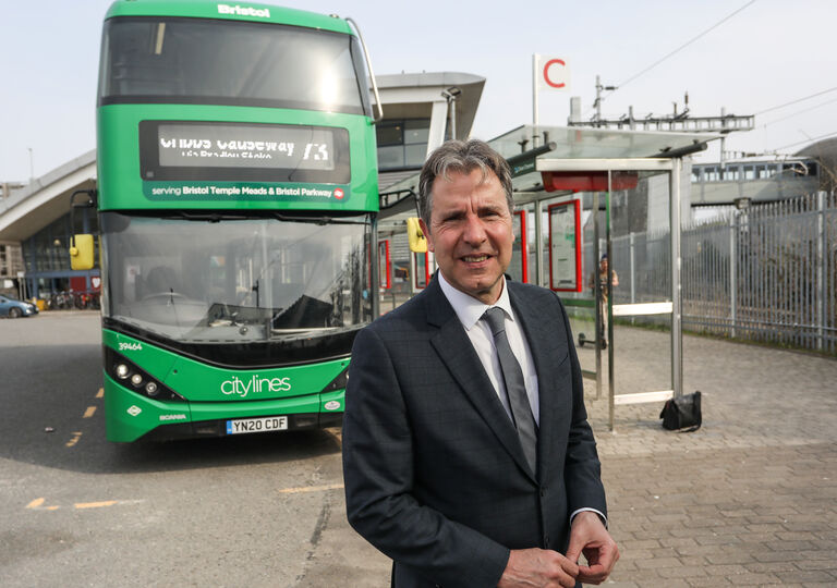 Metro Mayor Dan Norris at a bus station, with a bus stop and green double-decker bus behind him
