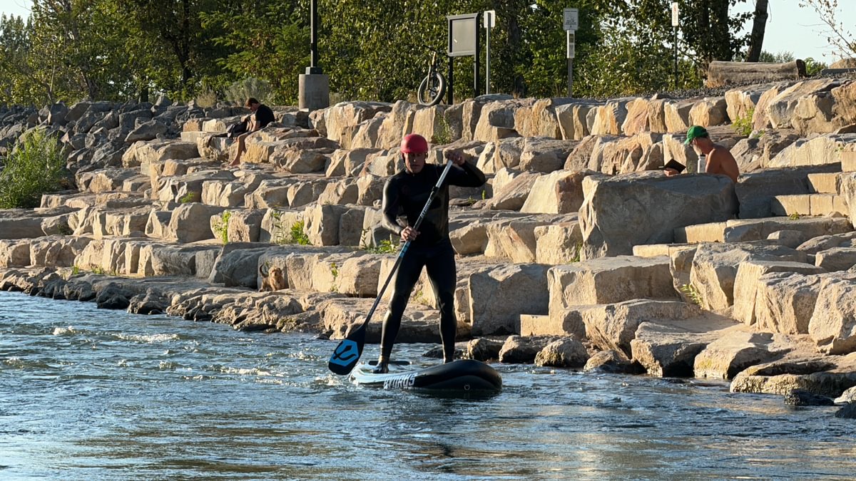 Man paddleboarding upstream on river