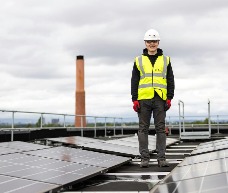 Person in hi-vis stands on a roof