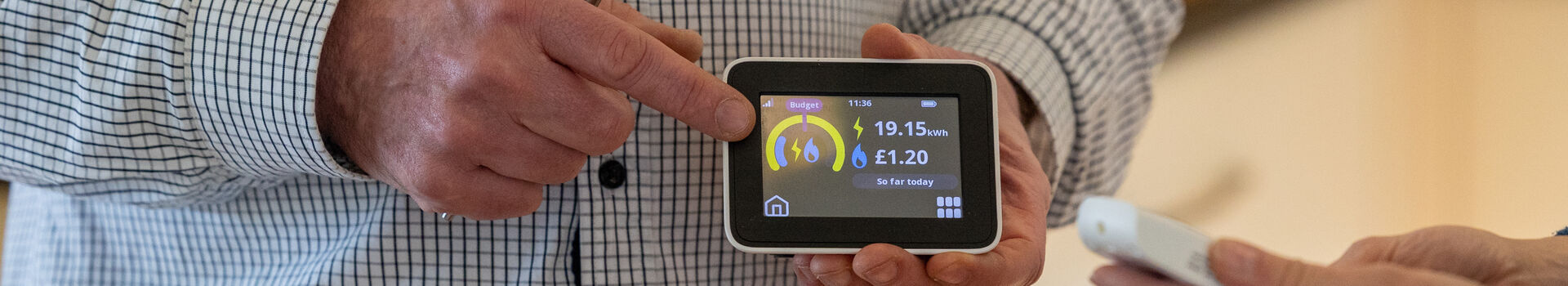 Person holding a smart meter showing their daily energy spend