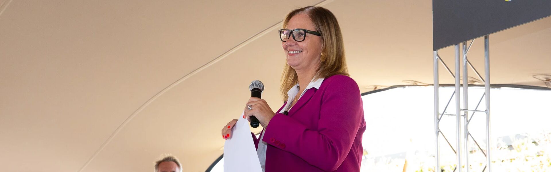 Helen Godwin smiling, giving a speech on stage
