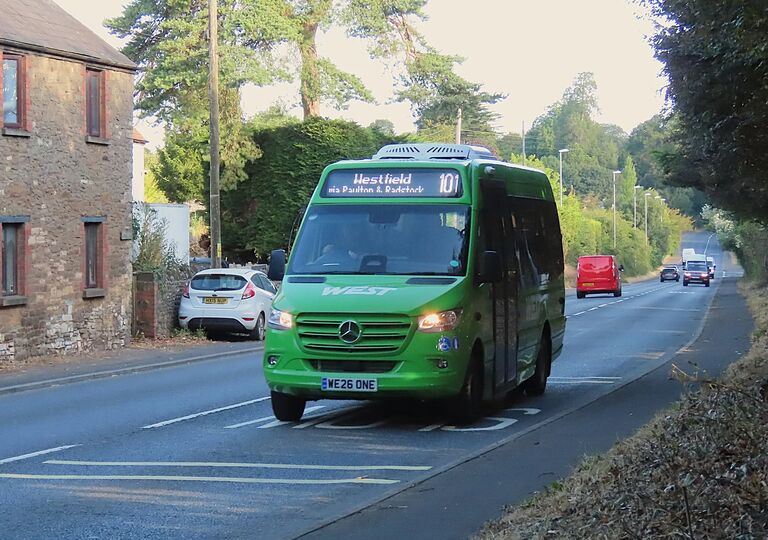 a green westlink bus driving on a road
