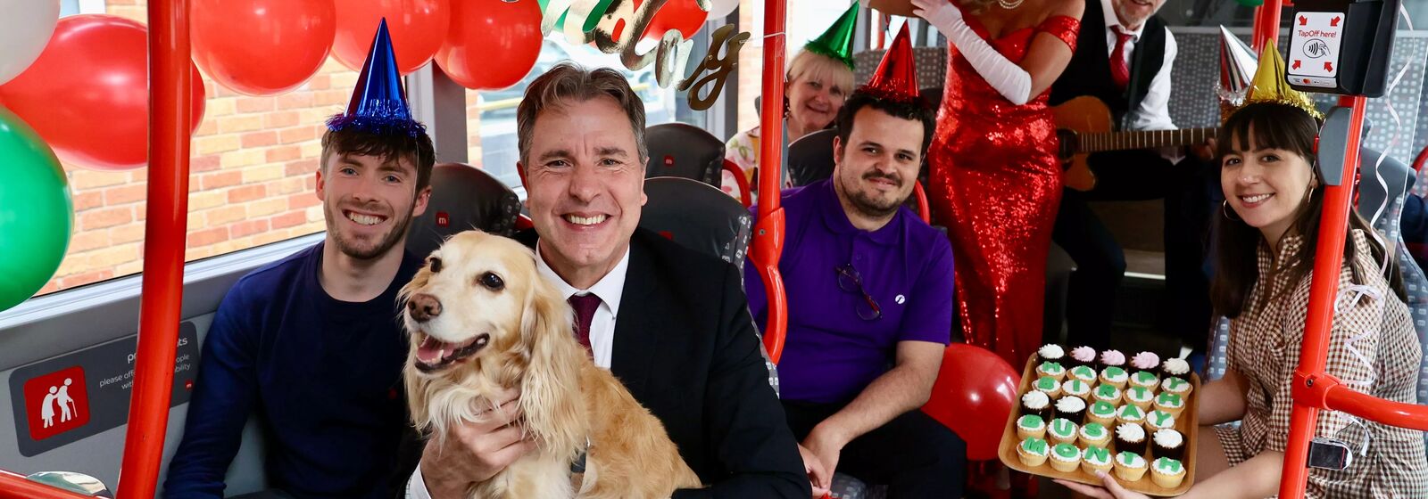 West of England Metro Mayor Dan Norris celebrating on the bus with his dog and others holding a cake