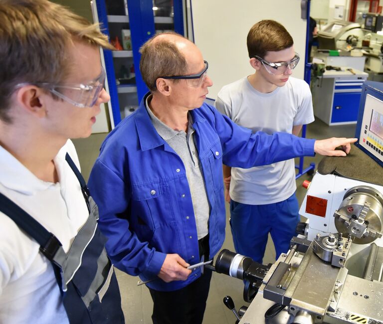 2 Interns or apprentices with a mentor in a CNC lab