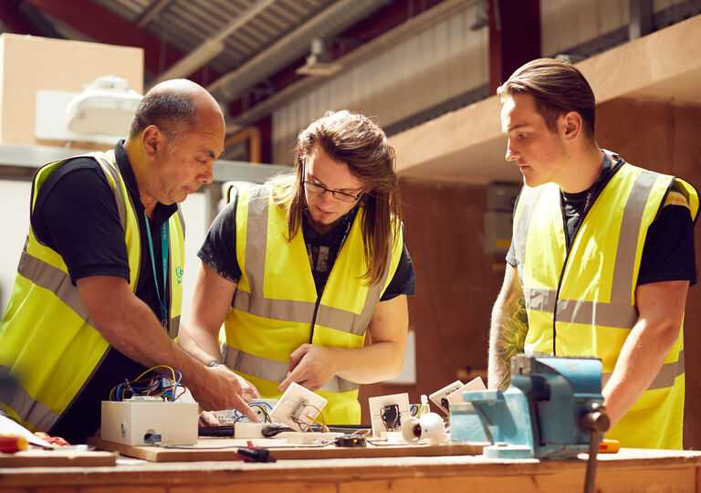 Group of electricians working at a table in hi-vis