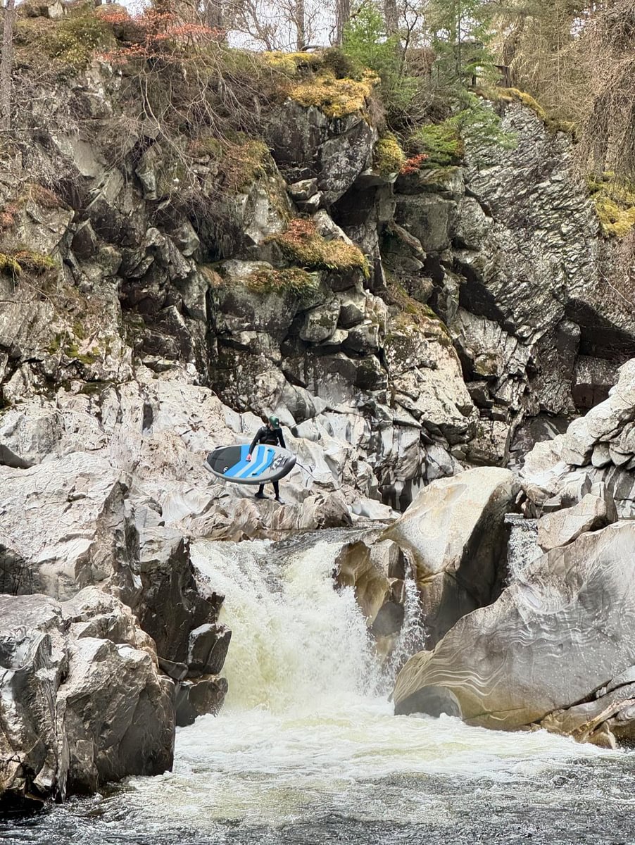 white water paddle boarder about to go down small waterfall