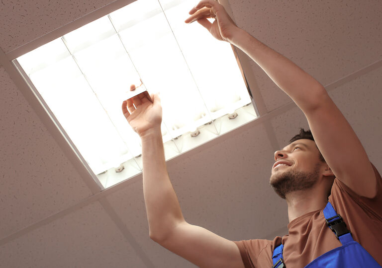 Man fixing an overhead light bulb strip