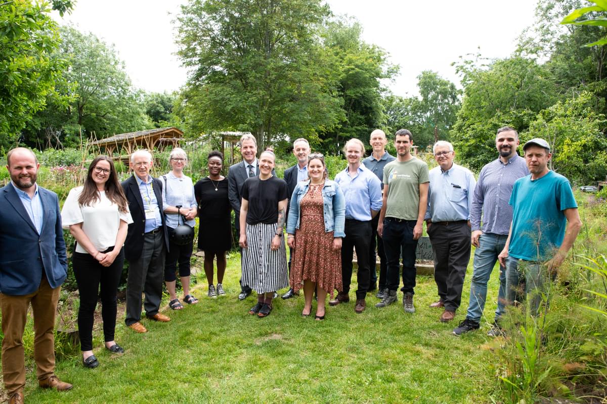 Group of people with Metro Mayor Dan Norris at Windmill Hill City Farm. They are all stood in a field surrounded by trees and grass.