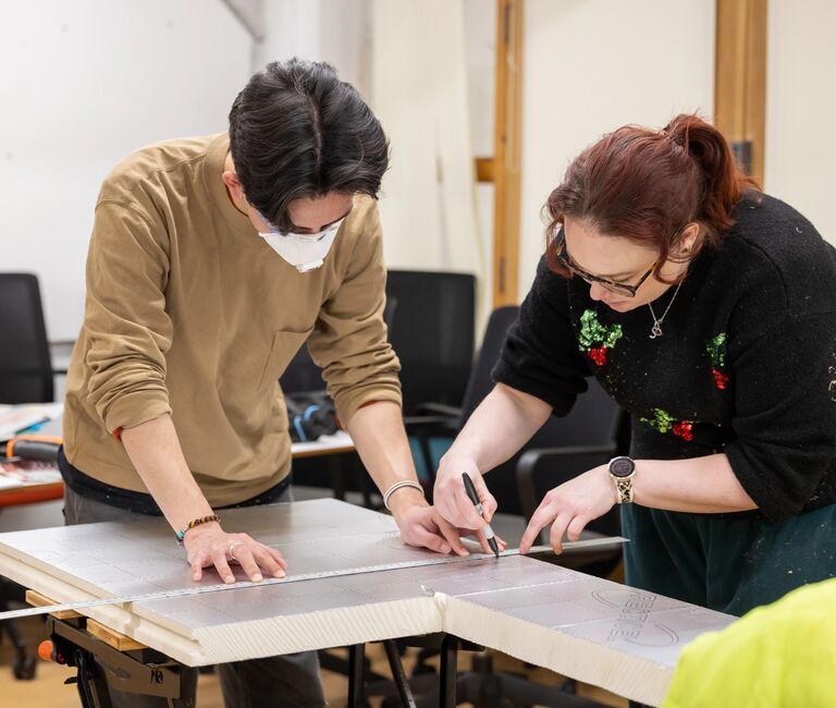 Two people sawing insulation