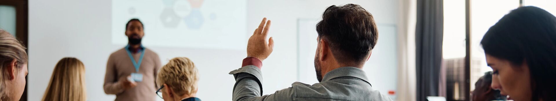 Man with hand up in classroom