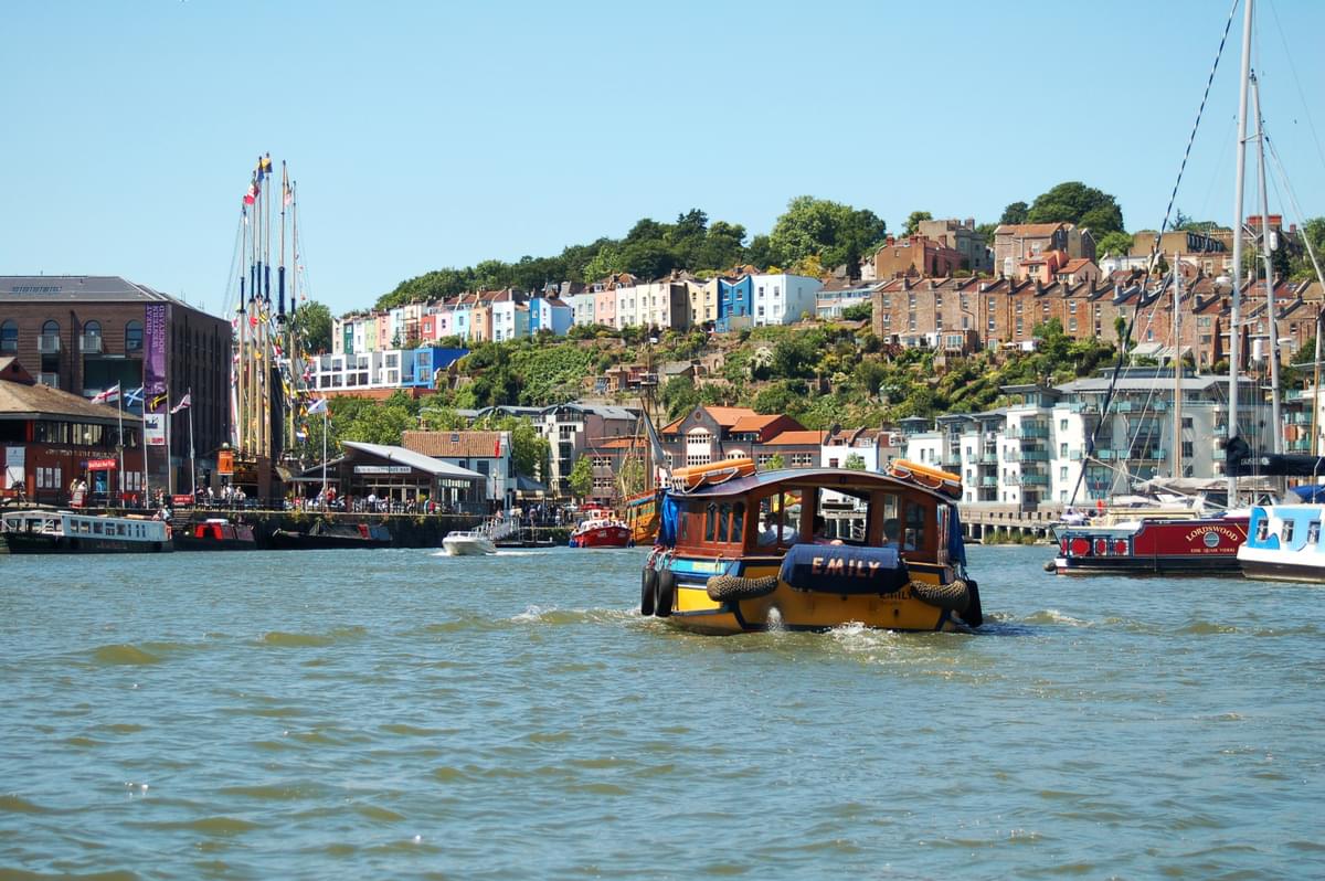Bristol Harbourside - a row of colourful houses in Bristol with the river in front and a boat 
